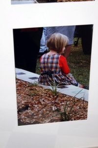 A child sitting on the edge of a garden bed / grave