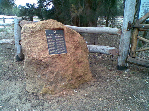 Plaque embedded into a rock in front of a wooden fence