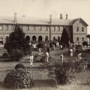 Photo showing a long view of a three-storey building with gardens around it
